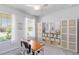 Well-lit home office features a ceiling fan, large windows, a desk, and built-in storage shelves at 20389 Minuet Pl, Venice, FL 34293