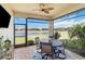Relax on this screened lanai featuring a ceiling fan, stylish outdoor furniture, and a serene water view at 20389 Minuet Pl, Venice, FL 34293