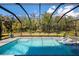 Sparkling swimming pool with a screened enclosure surrounded by lush landscaping and lounge chairs at 2042 Mesic Hammock Way, Venice, FL 34292