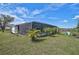Backyard view of the house with tropical landscaping, screened-in pool, and outdoor seating area at 2114 S Biscayne Dr, North Port, FL 34287