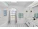 Bright main bathroom with white cabinets, tub with shower, and a large window at 2114 S Biscayne Dr, North Port, FL 34287