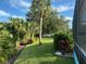Well-maintained backyard with green grass, palm trees, garden beds, and white privacy fence at 213 Bayside Ct, Nokomis, FL 34275