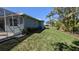 View of home side yard showing lush lawn, trees, and a screened lanai at 213 Bayside Ct, Nokomis, FL 34275