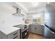 Bright kitchen with stainless steel appliances, grey cabinets, quartz countertops, and floating shelves at 236 Harbor S Dr # 202, Venice, FL 34285