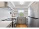 Bright kitchen with stainless steel appliances, grey cabinets, quartz countertops, and floating shelves at 236 Harbor S Dr # 202, Venice, FL 34285