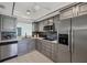 Well-lit kitchen features stainless steel appliances, gray cabinets, tile backsplash and ceiling fan at 275 Mission W Trl # G, Venice, FL 34285