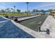 Bocce ball courts with dark green turf and grey borders are sheltered by shade structures and landscaping at 29176 Coral Harbour Dr, Englewood, FL 34223