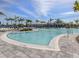 Large community pool with ample lounge seating, blue umbrellas and poolside dining surrounded by palm trees at 29176 Coral Harbour Dr, Englewood, FL 34223