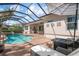 Outdoor living space with pool, lounge chairs, fire table, and screened enclosure at 297 Martellago Dr, North Venice, FL 34275