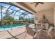 Covered patio with outdoor kitchen, dining area, and view of the screened pool at 297 Martellago Dr, North Venice, FL 34275