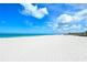 Expansive beach of pristine white sand meeting a turquoise ocean under a vibrant blue sky filled with fluffy white clouds at 417 Shore Rd # A & B, Nokomis, FL 34275