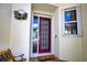 Inviting entryway with a decorative wreath, red front door, a cute rug, and a window with white trim at 4398 Summertree Rd, Venice, FL 34293