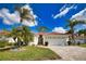 Charming home with a well-manicured lawn, beautiful palm trees, and a brick driveway leading to a two-car garage at 4398 Summertree Rd, Venice, FL 34293