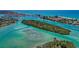 Scenic aerial view of an island community with lush vegetation and boats navigating waterways at 471 Bayshore Rd, Nokomis, FL 34275