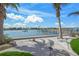Scenic waterfront view with a dock, palm trees, lush landscaping, and a boat cruising by at 471 Bayshore Rd, Nokomis, FL 34275
