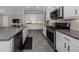 Spacious kitchen featuring modern appliances, gray countertops, and abundant white cabinetry with eat in area beyond at 500 Padova Way, North Venice, FL 34275