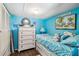 A turquoise bedroom with a twin bed, drawers, and wood-look flooring at 508 Blackburn Blvd, North Port, FL 34287