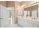 Bathroom featuring double sinks, granite countertop and white cabinetry with entry to the hallway at 632 Valencia Rd, Venice, FL 34285