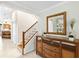 Welcoming foyer with staircase, tile flooring, decorative mirror and console table near kitchen and doorway at 632 Valencia Rd, Venice, FL 34285