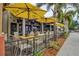 View of an outdoor restaurant patio with tables, chairs and yellow umbrellas at 632 Valencia Rd, Venice, FL 34285