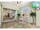 Bright sunroom with palm leaf rug, television, bar-height seating, and sliding glass doors to interior living spaces at 632 Valencia Rd, Venice, FL 34285