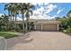 Elegant home showcasing a brick driveway, lush landscaping, and a spacious three-car garage at 7120 Grassland Ct, Sarasota, FL 34241