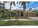 Charming home featuring a tile roof, arched entry, and a beautifully landscaped front yard with mature palm trees at 7120 Grassland Ct, Sarasota, FL 34241