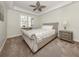 Inviting bedroom featuring a stylish bed with nailhead trim, a nightstand, and a leafy ceiling fan at 830 The Esplanade N # 201, Venice, FL 34285