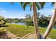 Scenic backyard view of the lake, lush lawn and landscaping with mature trees at 832 Saintclair Cir # 832, Venice, FL 34285