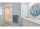 Bright bathroom featuring a vanity with storage, a decorative mirror, and a shower-over-tub with glass doors at 8603 46Th Avenue W Cir, Bradenton, FL 34210