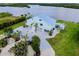 Expansive aerial view of light blue house with metal roof, pool, lush landscaping, and water views at 9061 Kellogg Ln, Venice, FL 34293