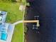 Aerial of waterfront home with a dock, boat lift, pool, and lush landscaping at 9061 Kellogg Ln, Venice, FL 34293