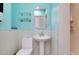 Bright teal bathroom with white fixtures, glass shelves, and an octagon mirror at 9061 Kellogg Ln, Venice, FL 34293