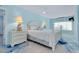 Coastal bedroom featuring a white bed frame, blue walls, ceiling fan and a lamp at 9061 Kellogg Ln, Venice, FL 34293