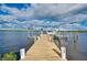 Long wooden dock extending into calm waters with boat lift; blue skies above at 9061 Kellogg Ln, Venice, FL 34293