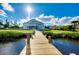 Wooden dock leading to a house with manicured lawn and lush landscaping at 9061 Kellogg Ln, Venice, FL 34293
