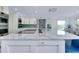 Gourmet kitchen featuring white cabinets, stainless appliances, and a large white marble island with cooktop at 9061 Kellogg Ln, Venice, FL 34293