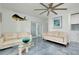 Bright living room with white couches, glass coffee table, and blue accent flooring and decor at 9061 Kellogg Ln, Venice, FL 34293
