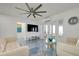 Bright living room with white couches, glass coffee table, and blue accent flooring and decor at 9061 Kellogg Ln, Venice, FL 34293