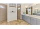 Bathroom with double vanity, marble flooring, walk-in shower with dual shower heads, and an arched window for natural light at 9407 Prospect Ave, Englewood, FL 34224