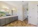 Bathroom with marble flooring, gray cabinets, double sinks, a large mirror, and entryways to the walk-in shower at 9407 Prospect Ave, Englewood, FL 34224