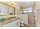 Bathroom featuring granite counters, white cabinets, walk-in glass enclosed shower with tile accents, and an oval mirror at 9407 Prospect Ave, Englewood, FL 34224