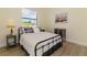 Bedroom featuring a metal frame bed, wood-look flooring, a neutral color scheme, and a sunny window with blinds at 9407 Prospect Ave, Englewood, FL 34224