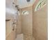 Luxurious shower with a rainfall showerhead, handheld shower, built-in niche, and an arched window for natural lighting at 9407 Prospect Ave, Englewood, FL 34224
