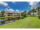 Scenic backyard featuring lush green lawn and a dock overlooking a tranquil pond at 410 Mission E Trl # H, Venice, FL 34285