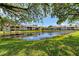 Scenic view of a pond with a wooden dock, surrounded by lush green lawns and well-maintained community buildings at 410 Mission E Trl # H, Venice, FL 34285