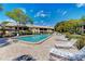 Outdoor pool with brick pavers and lounge chairs, with a view of the community buildings and tropical landscaping at 410 Mission E Trl # H, Venice, FL 34285