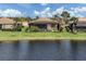 View of back of home featuring lake view and enclosed patio with lush landscaping at 129 Cipriani Way, North Venice, FL 34275