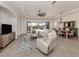 Bright living room featuring neutral tile flooring, a ceiling fan, and sliding doors leading to the pool area at 129 Cipriani Way, North Venice, FL 34275