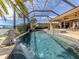 View of screened in pool and spa with waterfalls and lounge area overlooking lake at 129 Cipriani Way, North Venice, FL 34275